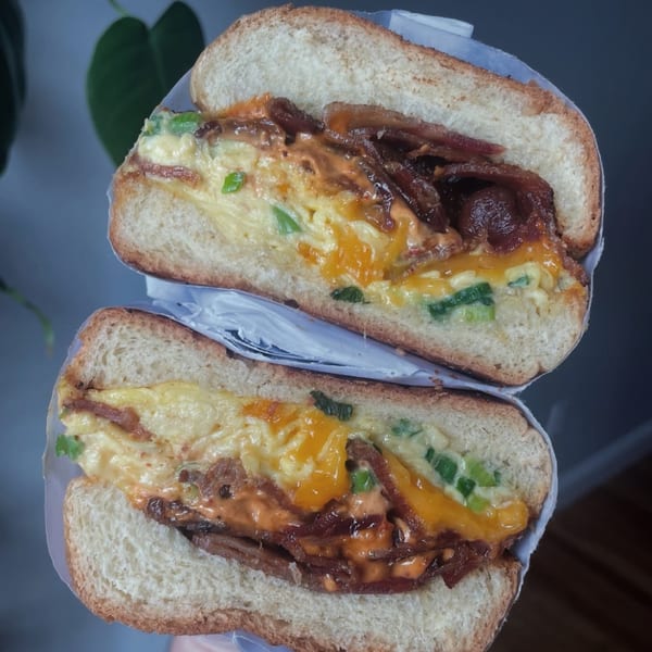 Emma's Deli breakfast sandwich with scrambled eggs, cheese, bacon, and green onions on a roll.