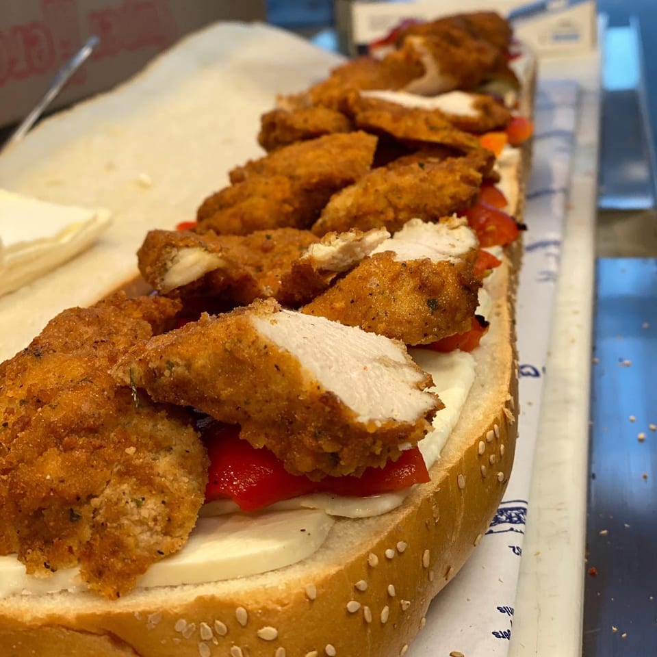 A long deli sandwich filled with crispy chicken cutlets, red peppers, and fresh mozzarella cheese.
